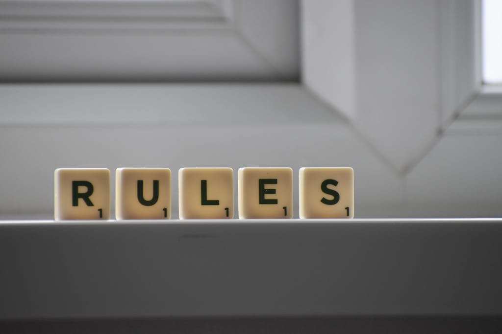 Identical small square shaped cubes with RULES title and numbers on white windowsill near window in house in daylight - Disclaimer